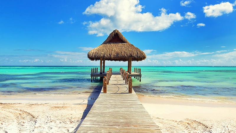 Palm leaf roofed wooden pier with gazebo on the beach