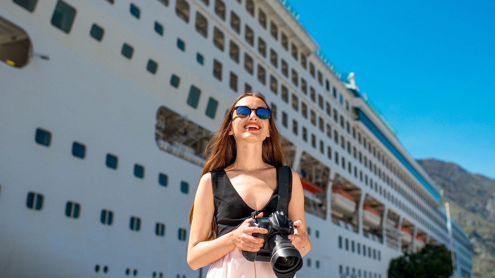 woman with camera standing in front of cruise ship