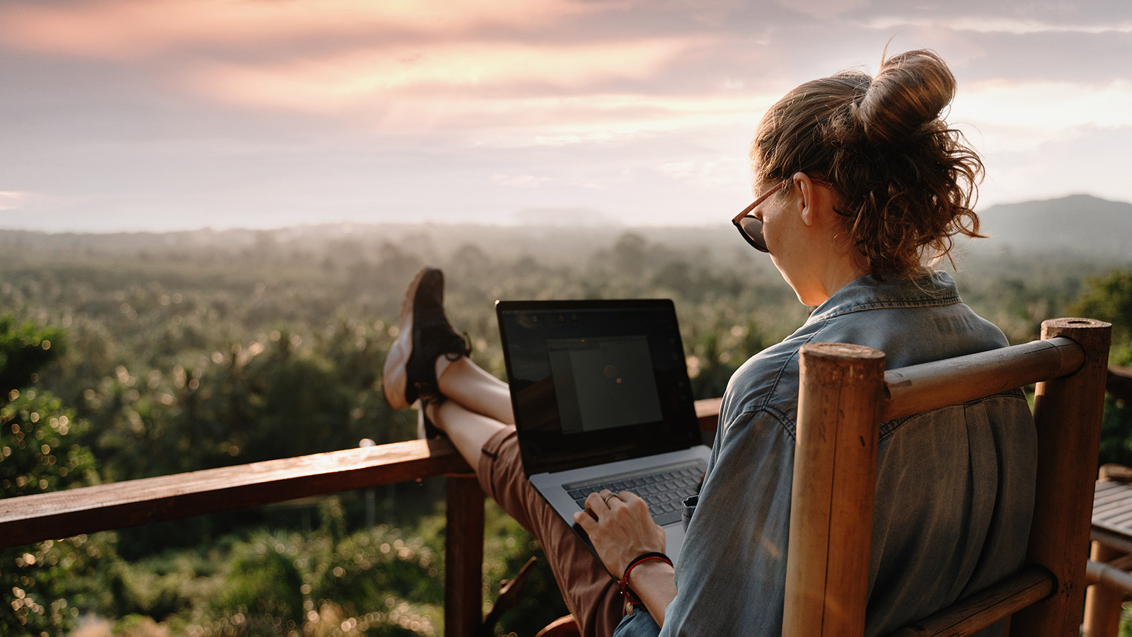 Young girl using a laptop at sunset