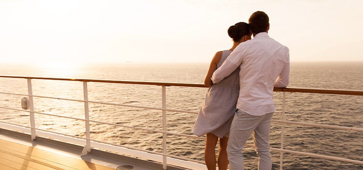 young couple hugging at sunset on cruise ship