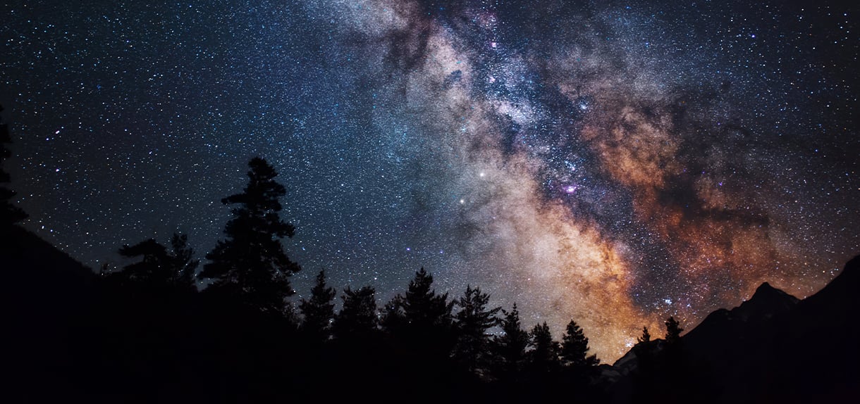 Astrophotography of Milky Way galaxy with the silhouette of mountains trees at the bottom